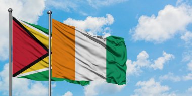 Guyana ve Fildişi Sahili bayrağı birlikte beyaz bulutlu mavi gökyüzüne karşı rüzgarda sallayarak. Diplomasi kavramı, uluslararası ilişkiler.