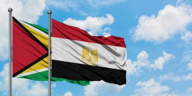 Guyana ve Mısır bayrağı birlikte beyaz bulutlu mavi gökyüzüne karşı rüzgarda sallayarak. Diplomasi kavramı, uluslararası ilişkiler.