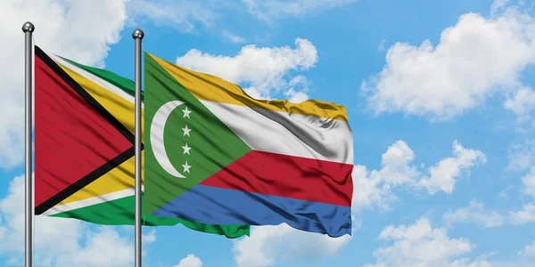 Guyana e Comore sventolano nel vento contro il bianco cielo blu nuvoloso insieme. Concetto di diplomazia, relazioni internazionali . — Foto Stock