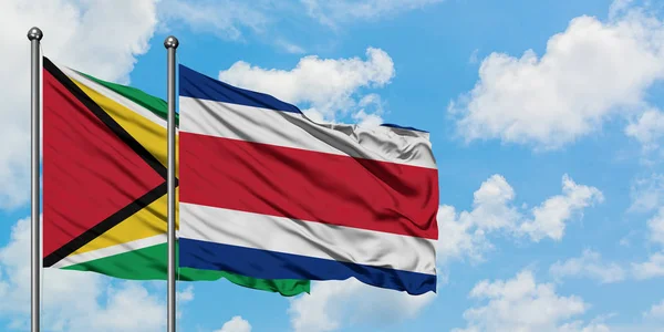 Guyana ve Kosta Rika bayrağı birlikte beyaz bulutlu mavi gökyüzüne karşı rüzgarda sallayarak. Diplomasi kavramı, uluslararası ilişkiler. — Stok fotoğraf