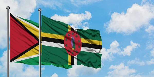 Bandera de Guyana y Dominica ondeando en el viento contra el cielo azul nublado blanco juntos. Concepto diplomático, relaciones internacionales . — Foto de Stock