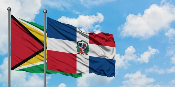 Bandera de Guyana y República Dominicana ondeando en el viento contra el cielo azul nublado blanco juntos. Concepto diplomático, relaciones internacionales . — Foto de Stock