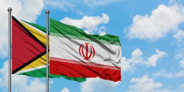 Guyana ve İran bayrağı birlikte beyaz bulutlu mavi gökyüzüne karşı rüzgarda sallayarak. Diplomasi kavramı, uluslararası ilişkiler.