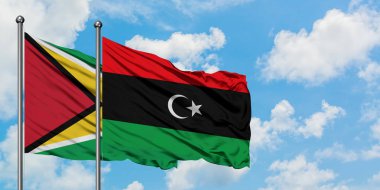 Guyana ve Libya bayrağı birlikte beyaz bulutlu mavi gökyüzüne karşı rüzgarda sallayarak. Diplomasi kavramı, uluslararası ilişkiler.