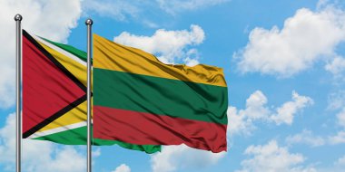 Guyana ve Litvanya bayrağı birlikte beyaz bulutlu mavi gökyüzüne karşı rüzgarda sallayarak. Diplomasi kavramı, uluslararası ilişkiler.