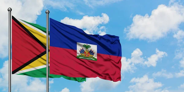 Guyana ve Haiti bayrağı birlikte beyaz bulutlu mavi gökyüzüne karşı rüzgarda sallayarak. Diplomasi kavramı, uluslararası ilişkiler. — Stok fotoğraf