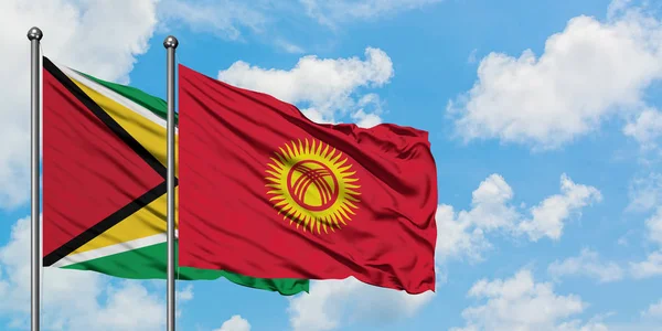 Guyana and Kyrgyzstan flag waving in the wind against white cloudy blue sky together. Diplomacy concept, international relations. — Stock Photo, Image