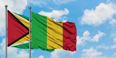 Guyana ve Mali bayrağı birlikte beyaz bulutlu mavi gökyüzüne karşı rüzgarda sallayarak. Diplomasi kavramı, uluslararası ilişkiler.