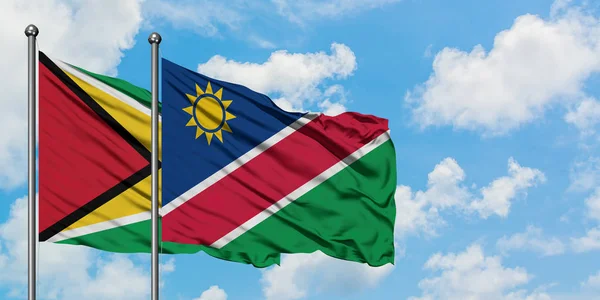 Guyana és Namíbia zászló integetett a szél ellen, fehér felhős kék eget együtt. Diplomáciai koncepció, nemzetközi kapcsolatok. — Stock Fotó