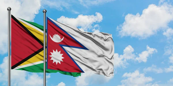 Bandera de Guyana y Nepal ondeando en el viento contra el cielo azul nublado blanco juntos. Concepto diplomático, relaciones internacionales . — Foto de Stock