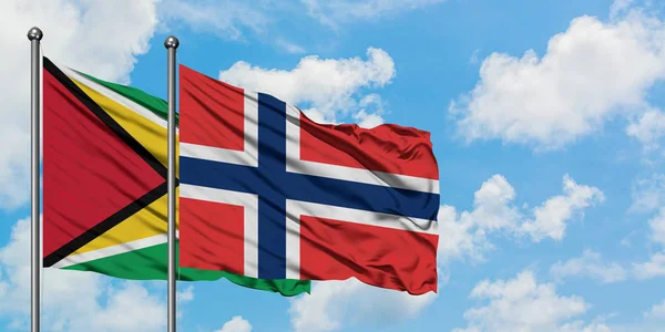 Bandera de Guyana y Noruega ondeando en el viento contra el cielo azul nublado blanco juntos. Concepto diplomático, relaciones internacionales . — Foto de Stock