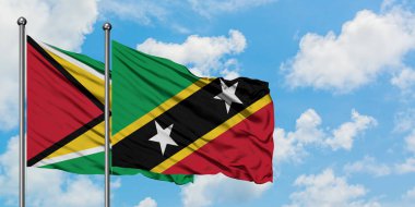 Guyana ve Saint Kitts ve Nevis bayrağı birlikte beyaz bulutlu mavi gökyüzüne karşı rüzgarda sallayarak. Diplomasi kavramı, uluslararası ilişkiler.
