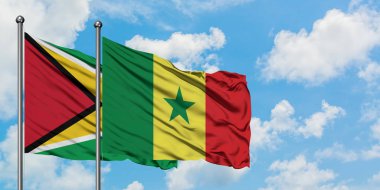 Guyana ve Senegal bayrağı birlikte beyaz bulutlu mavi gökyüzüne karşı rüzgarda sallayarak. Diplomasi kavramı, uluslararası ilişkiler.