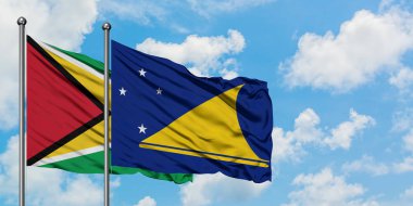 Guyana ve Tokelau bayrağı birlikte beyaz bulutlu mavi gökyüzüne karşı rüzgarda sallayarak. Diplomasi kavramı, uluslararası ilişkiler.