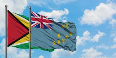 Guyana ve Tuvalu bayrağı birlikte beyaz bulutlu mavi gökyüzüne karşı rüzgarda sallayarak. Diplomasi kavramı, uluslararası ilişkiler.