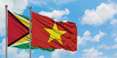 Guyana ve Vietnam bayrağı birlikte beyaz bulutlu mavi gökyüzüne karşı rüzgarda sallayarak. Diplomasi kavramı, uluslararası ilişkiler.