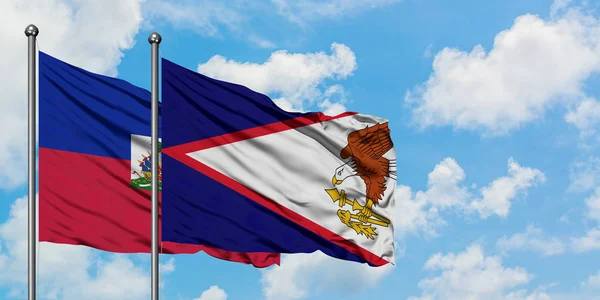 Haiti i Samoa Amerykańskie flagi machając w wiatr przed białym zachmurzone błękitne niebo razem. Koncepcja dyplomacji, stosunki międzynarodowe. — Zdjęcie stockowe