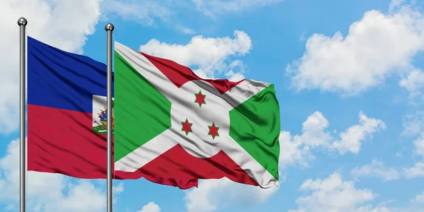 Bandera de Haití y Burundi ondeando en el viento contra el cielo azul nublado blanco juntos. Concepto diplomático, relaciones internacionales . — Foto de Stock