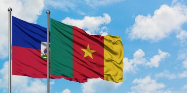 Haiti ve Kamerun bayrağı birlikte beyaz bulutlu mavi gökyüzüne karşı rüzgarda sallayarak. Diplomasi kavramı, uluslararası ilişkiler.