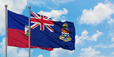 Haiti ve Cayman Adaları bayrağı birlikte beyaz bulutlu mavi gökyüzüne karşı rüzgarda sallayarak. Diplomasi kavramı, uluslararası ilişkiler.