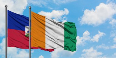 Haiti ve Fildişi Sahili bayrağı birlikte beyaz bulutlu mavi gökyüzüne karşı rüzgarda sallayarak. Diplomasi kavramı, uluslararası ilişkiler.