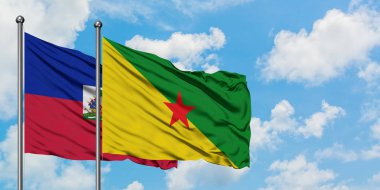 Haiti ve Fransız Guyanası bayrağı birlikte beyaz bulutlu mavi gökyüzüne karşı rüzgarda sallayarak. Diplomasi kavramı, uluslararası ilişkiler.