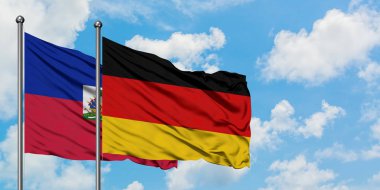 Haiti ve Almanya bayrağı birlikte beyaz bulutlu mavi gökyüzüne karşı rüzgarsal sallayarak. Diplomasi kavramı, uluslararası ilişkiler.