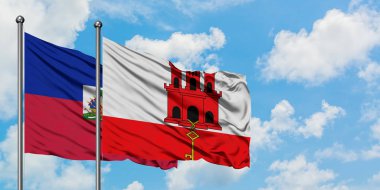 Haiti ve Cebelitarık bayrağı birlikte beyaz bulutlu mavi gökyüzüne karşı rüzgarda sallayarak. Diplomasi kavramı, uluslararası ilişkiler.