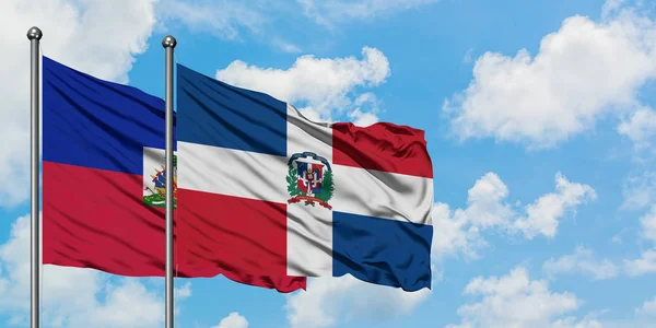 一緒に白い曇った青い空に対して風に手を振るハイチとドミニカ共和国の旗。外交概念、国際関係. — ストック写真