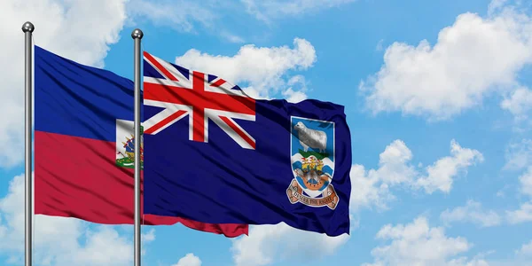 Bandera de Haití e Islas Malvinas ondeando en el viento contra el cielo azul nublado blanco juntos. Concepto diplomático, relaciones internacionales . — Foto de Stock