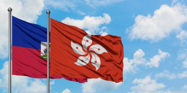 Haiti ve Hong Kong bayrağı birlikte beyaz bulutlu mavi gökyüzüne karşı rüzgarda sallayarak. Diplomasi kavramı, uluslararası ilişkiler.