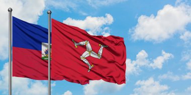 Haiti ve Isle Of Man bayrağı birlikte beyaz bulutlu mavi gökyüzüne karşı rüzgarda sallayarak. Diplomasi kavramı, uluslararası ilişkiler.