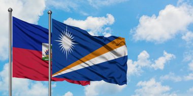 Haiti ve Marshall Adaları bayrağı birlikte beyaz bulutlu mavi gökyüzüne karşı rüzgarda sallayarak. Diplomasi kavramı, uluslararası ilişkiler.