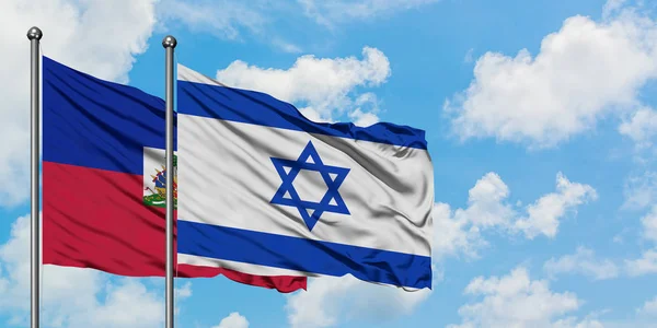 A bandeira do Haiti e de Israel agitando no vento contra o céu azul nublado branco juntos. Conceito de diplomacia, relações internacionais . — Fotografia de Stock