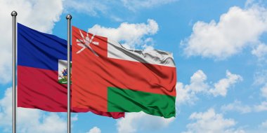 Haiti ve Umman bayrağı birlikte beyaz bulutlu mavi gökyüzüne karşı rüzgarda sallayarak. Diplomasi kavramı, uluslararası ilişkiler.