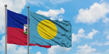 Haiti ve Palau bayrağı birlikte beyaz bulutlu mavi gökyüzüne karşı rüzgarda sallayarak. Diplomasi kavramı, uluslararası ilişkiler.