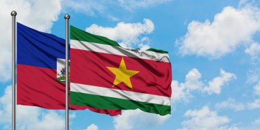 Haiti ve Surinam bayrağı birlikte beyaz bulutlu mavi gökyüzüne karşı rüzgarda sallayarak. Diplomasi kavramı, uluslararası ilişkiler.