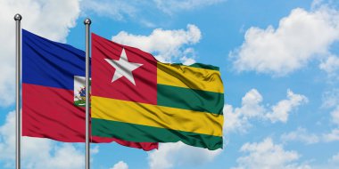 Haiti ve Togo bayrağı birlikte beyaz bulutlu mavi gökyüzüne karşı rüzgarda sallayarak. Diplomasi kavramı, uluslararası ilişkiler.