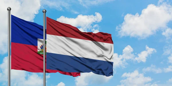 Haiti e Paesi Bassi sventolano insieme la bandiera contro il bianco cielo blu nuvoloso. Concetto di diplomazia, relazioni internazionali . — Foto Stock