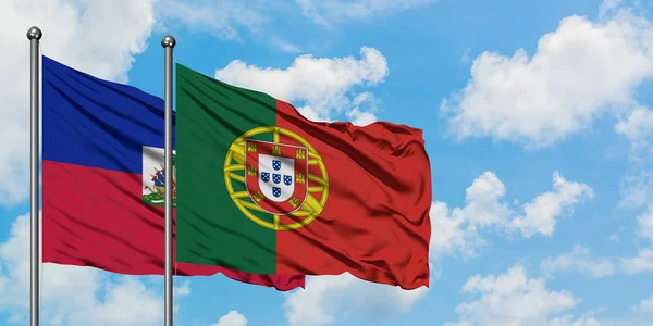 Bandera de Haití y Portugal ondeando en el viento contra el cielo azul nublado blanco juntos. Concepto diplomático, relaciones internacionales . — Foto de Stock