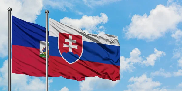 Bandera de Haití y Eslovaquia ondeando en el viento contra el cielo azul nublado blanco juntos. Concepto diplomático, relaciones internacionales . — Foto de Stock