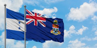 Honduras ve Cayman Adaları bayrağı birlikte beyaz bulutlu mavi gökyüzüne karşı rüzgarda sallayarak. Diplomasi kavramı, uluslararası ilişkiler.