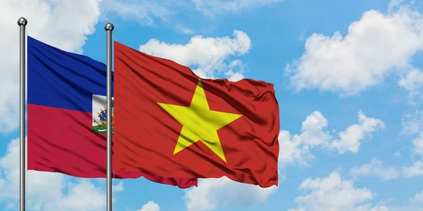 Bandera de Haití y Vietnam ondeando en el viento contra el cielo azul nublado blanco juntos. Concepto diplomático, relaciones internacionales . — Foto de Stock