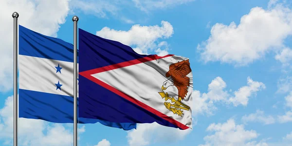 Bandera de Honduras y Samoa Americana ondeando en el viento contra el cielo azul nublado blanco juntos. Concepto diplomático, relaciones internacionales . —  Fotos de Stock