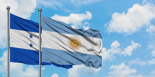 Bandera de Honduras y Argentina ondeando en el viento contra el cielo azul nublado blanco juntos. Concepto diplomático, relaciones internacionales . —  Fotos de Stock
