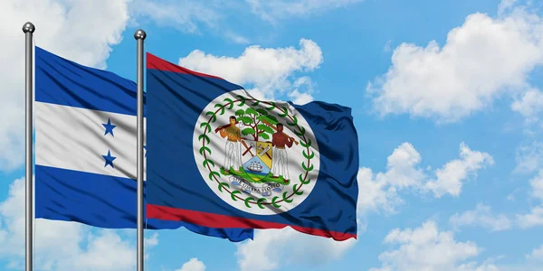 Bandera de Honduras y Belice ondeando en el viento contra el cielo azul nublado blanco juntos. Concepto diplomático, relaciones internacionales . — Foto de Stock