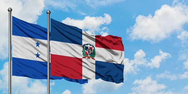 Bandera de Honduras y República Dominicana ondeando en el viento contra el cielo azul nublado blanco juntos. Concepto diplomático, relaciones internacionales . — Foto de Stock