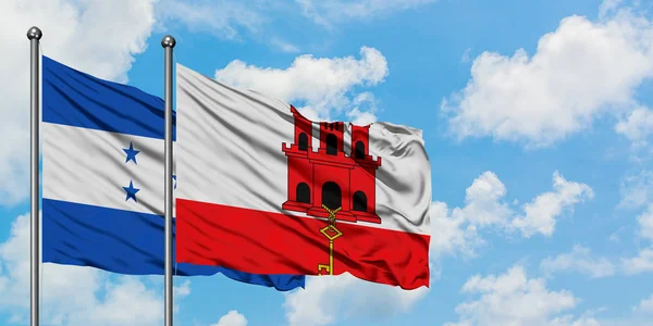 Гондурас і Гібралтар прапор розмахував вітром проти білого хмарного синього неба разом. Концепція дипломатії, міжнародні відносини. — стокове фото