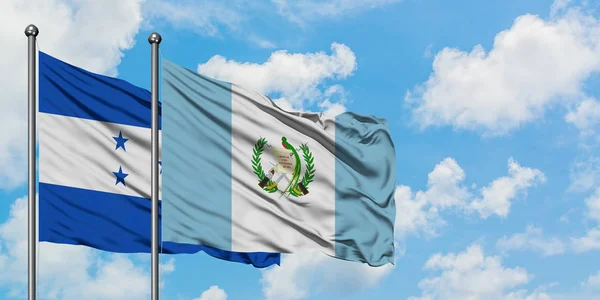Bandera de Honduras y Guatemala ondeando en el viento contra el cielo azul nublado blanco juntos. Concepto diplomático, relaciones internacionales . — Foto de Stock