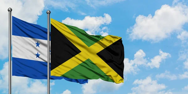 Bandera de Honduras y Jamaica ondeando en el viento contra el cielo azul nublado blanco juntos. Concepto diplomático, relaciones internacionales . — Foto de Stock